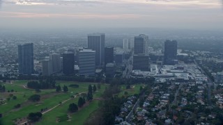 AX0156_132 - 7.6K aerial stock footage flying over golf course along office buildings and skyscrapers, sunrise, Century City, California