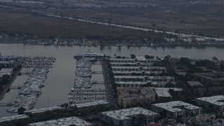 AX0156_174 - 7.6K aerial stock footage of a mega yacht docked in the harbor near waterfront apartment buildings at sunrise in Marina Del Rey, California 