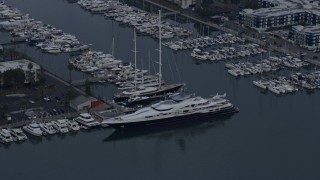 AX0156_177 - 7.6K aerial stock footage pulling away from a docked mega yacht with helicopter, sunrise, Marina Del Rey, California