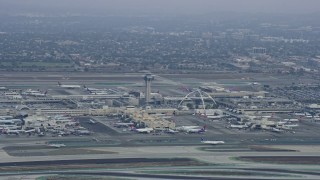 AX0156_190 - 7.6K aerial stock footage of LAX and its control tower on a cloudy morning, sunrise, Los Angeles, California