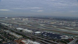 AX0156_192E - 7.6K aerial stock footage approaching LAX in the morning as a FedEx airplane starts down the runway, California