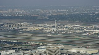 AX0157_004 - 7.6K aerial stock footage tracking a plane taking off from LAX, cloudy, Los Angeles, California