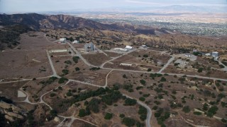 AX0157_047 - 7.6K stock footage aerial video approaching roads and buildings of the Rocektdyne aerospace testing facility, Brandeis, California