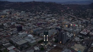 AX0158_017 - 7.6K aerial stock footage of businesses and office buildings along Sunset Boulevard at twilight, Hollywood, California