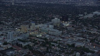 AX0158_039E - 7.6K aerial stock footage of Wilshire La Brea apartments and Consulate General of Spain on Wilshire Boulevard at twilight, Central Los Angeles, California
