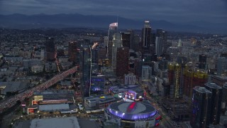 AX0158_045 - 7.6K stock footage aerial video orbiting Downtown Los Angeles skyscrapers, Interstate 110 and Staples Center at twilight, California