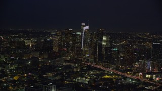 AX0158_090E - 7.6K aerial stock footage of 110 traffic by skyscrapers and Staples Center at night, Downtown Los Angeles, California