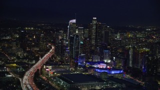 AX0158_091 - 7.6K stock footage aerial video of 110 traffic by skyscrapers and Staples Center at night, Downtown Los Angeles, California