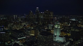 AX0158_109 - 7.6K stock footage aerial video of Downtown skyscrapers seen while flying by City Hall at night in Downtown Los Angeles, California