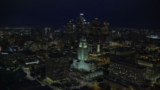 AX0158_109E - 7.6K aerial stock footage of Downtown skyscrapers seen while flying by City Hall at night in Downtown Los Angeles, California