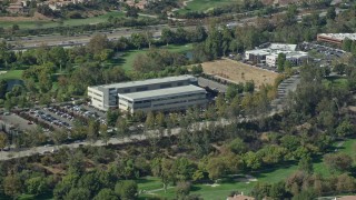 AX0159_030E - 7.6K aerial stock footage orbiting an office building and parking lot next to a golf course, Valencia, California