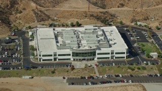 AX0159_041 - 7.6K stock footage aerial video passing by front of tech office building, Valencia, California