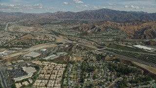 AX0159_050 - 7.6K stock footage aerial video flying over suburban housing toward highway and mountains, Santa Clarita, California