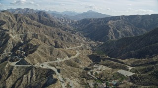 AX0159_055E - 7.6K aerial stock footage flying over a road winding through the canyons, Newhall, California