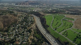 AX0159_131 - 7.6K stock footage aerial video following the I-10 freeway between homes and Forest Lawn Covina Hills Cemetery, Covina, California