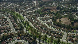 AX0159_134 - 7.6K stock footage aerial video flying by tract homes in a peaceful neighborhood in Pamona, California