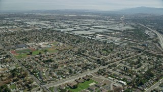 AX0159_136E - 7.6K aerial stock footage flying over homes and Don Antonio High School, approach warehouses, Chino, California