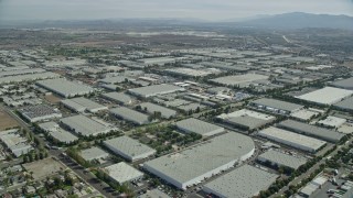 AX0159_137 - 7.6K stock footage aerial video flying over numerous large warehouses in Chino, California