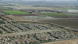 AX0159_139 - 7.6K stock footage aerial video flying over tract homes towards the East Yard of CIM Prison (California Institution for Men), Chino, California