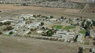 AX0159_144 - 7.6K stock footage aerial video passing by the California Institution for Men prison in Chino, California