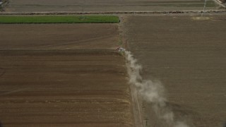 AX0159_150 - 7.6K aerial stock footage of a truck creating dust trail in farmland, Chino, California