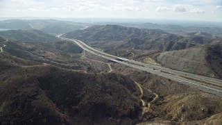 AX0159_158E - 7.6K aerial stock footage following a freeway through the hills, Anaheim, California
