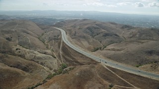 AX0159_162E - 7.6K aerial stock footage following a freeway with light traffic through the hills, Irvine, California