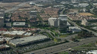 AX0159_168E - 7.6K aerial stock footage of office buildings and shopping mall along a freeway, Irvine, California
