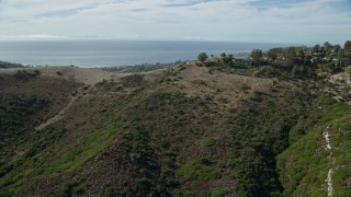 AX0159_215E - 7.6K aerial stock footage flying over hill to reveal coastal community below, Laguna Beach, California