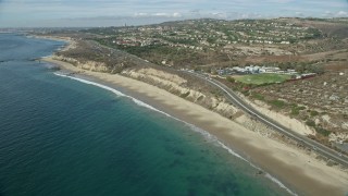 AX0159_228E - 7.6K aerial stock footage flying along beach near coastal highway, Newport Beach, California