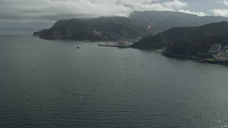 AX0159_261E - 7.6K aerial stock footage approaching boats anchored in Avalon Bay harbor by the island town on Santa Catalina Island, California