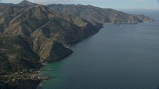 AX0159_266E - 7.6K aerial stock footage following the rugged coastline of Santa Catalina Island, California toward a campground