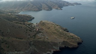 AX0160_005E - 7.6K aerial stock footage flying by coastal cliffs to approach the marine science center in Two Harbors, Santa Catalina Island, California