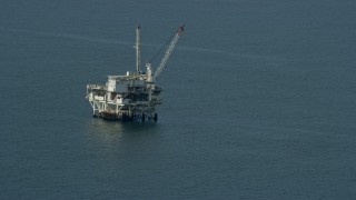 AX0160_037E - 7.6K aerial stock footage of an oceanic oil derrick off the coast of Southern California