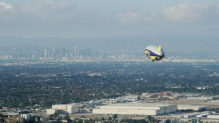 AX0160_062 - 7.6K stock footage aerial video of the Goodyear Blimp flying toward Downtown Los Angeles skyline from Long Beach Airport, California
