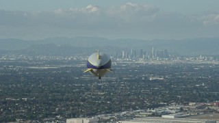 AX0160_062E - 7.6K aerial stock footage of the Goodyear Blimp flying toward Downtown Los Angeles skyline from Long Beach Airport, California
