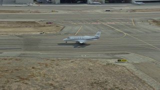 AX0160_068 - 7.6K aerial stock footage of a private jet taxiing down a runway at Long Beach Airport, California