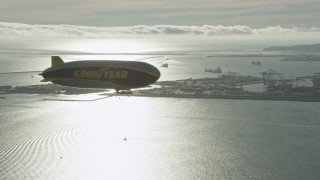 AX0161_005 - 7.6K aerial stock footage of the Goodyear Blimp flying by Downtown Long Beach, California