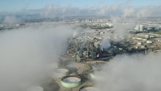 AX0161_042 - 7.6K stock footage aerial video flying over low level clouds to reveal the Chevron oil refinery in El Segundo, California