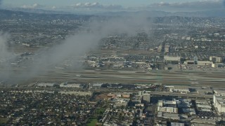AX0161_044 - 7.6K aerial stock footage approaching the airport, partially obscured by low level clouds, LAX, California