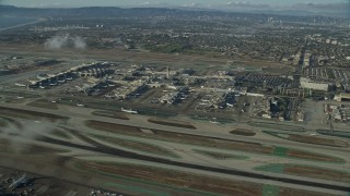 AX0161_045E - 7.6K aerial stock footage approaching the airport as airlines taxi on the runways, LAX, California