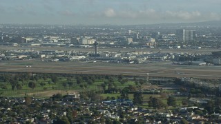 AX0161_050 - 7.6K aerial stock footage of LAX Airport as an airliner touches down on the runway, California