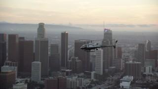 AX0162_094 - 7.6K stock footage aerial video LAPD helicopter flying by Downtown Los Angeles, California at twilight