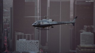 AX0162_095 - 7.6K stock footage aerial video tracking an LAPD helicopter flying by Downtown Los Angeles, California at twilight