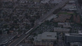AX0162_113 - 7.6K stock footage aerial video of a Metrolink commuter train passing neighborhoods at twilight in Burbank, California 