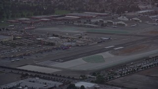 AX0162_114 - 7.6K aerial stock footage orbiting the end of a runway and terminals at twilight at Burbank Airport, California 
