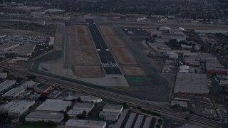 AX0162_116 - 7.6K aerial stock footage of a commercial airplane starting down the runway at Burbank Airport, California, twilight