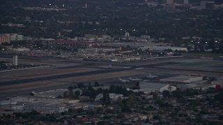 AX0162_117E - 7.6K aerial stock footage of a commercial airplane taking off at twilight from Burbank Airport, California