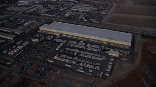 AX0162_119 - 7.6K aerial stock footage approaching and passing a large warehouse building in Pacoima, California at twilight