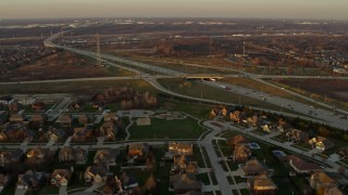 AX0163_0005 - 4K aerial stock footage fly over suburban homes and pass light freeway traffic at sunset in Lemont, Illinois
